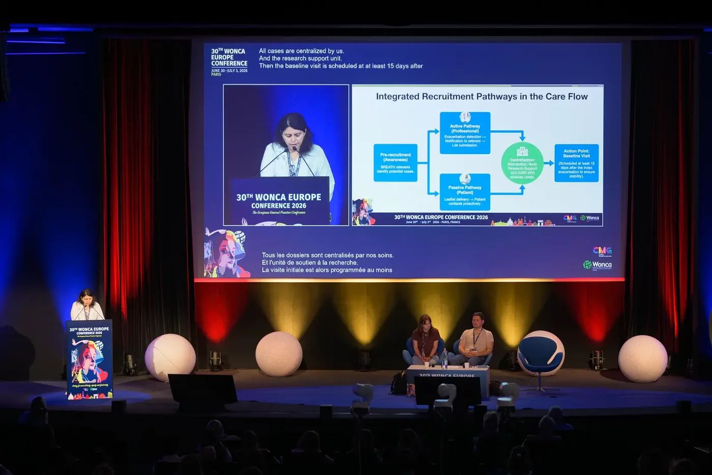 Conférence sur scène, salle plongée dans la pénombre